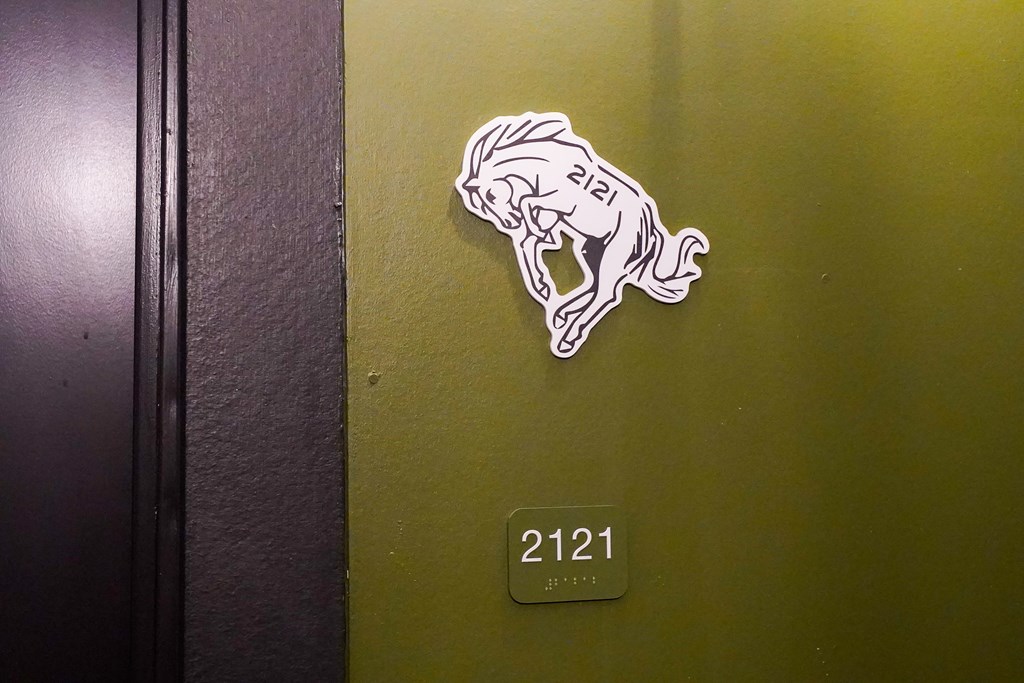 A door with a sticker of a horse and the number 2121.