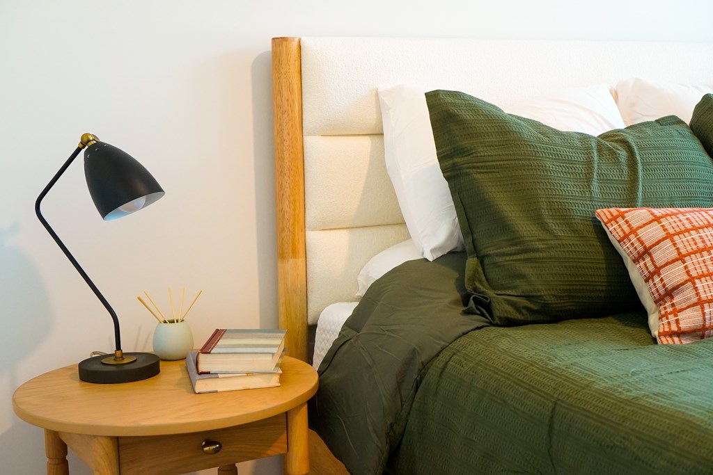 A bed with green pillows and a lamp on a side table.