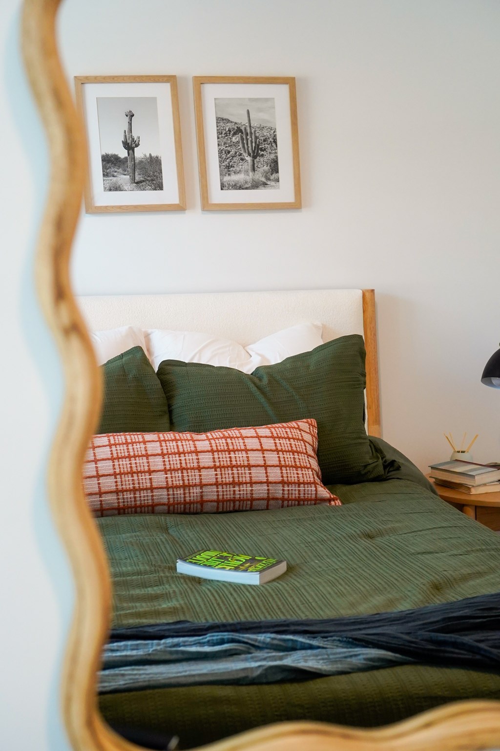 A bed with a green comforter and a book on it.