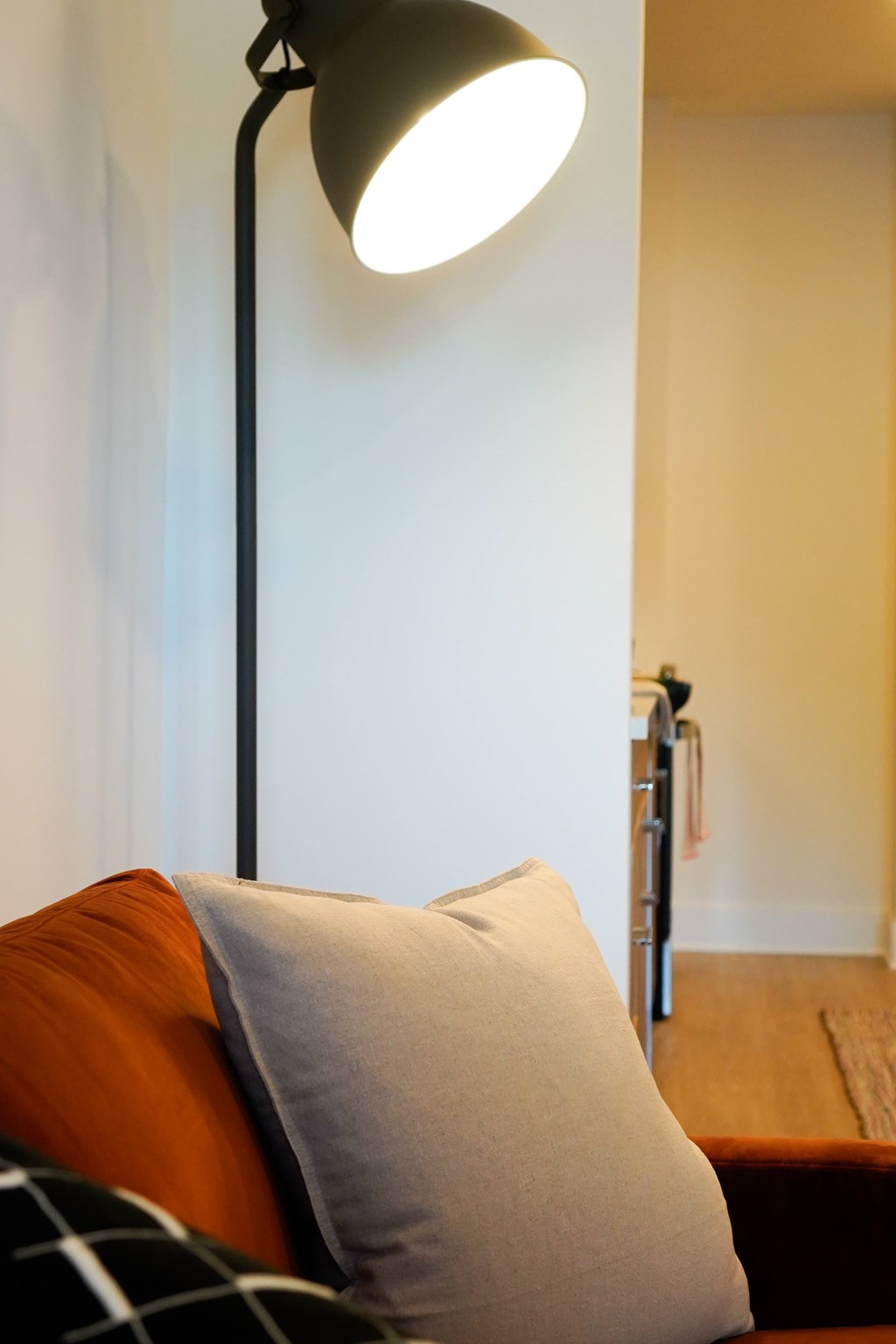 A lamp shines on a pillow on a couch.