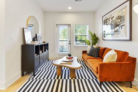 A living room with a brown couch and a black and white striped rug.