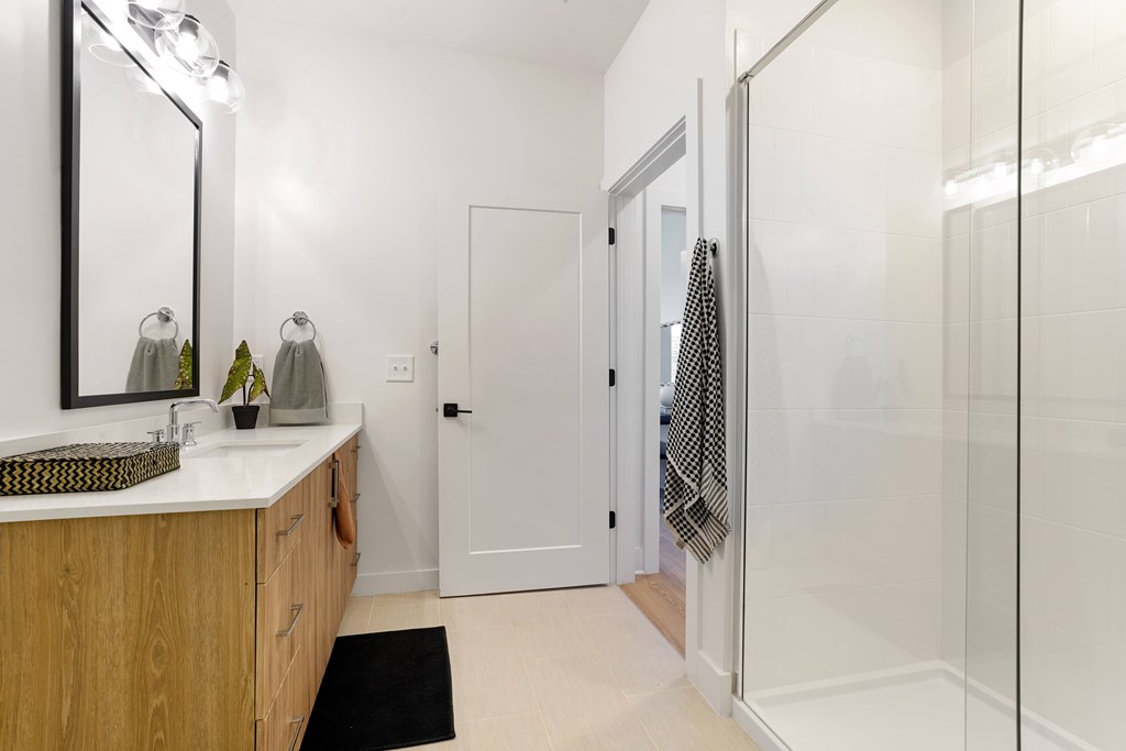 A bathroom with a sink, mirror, and shower.