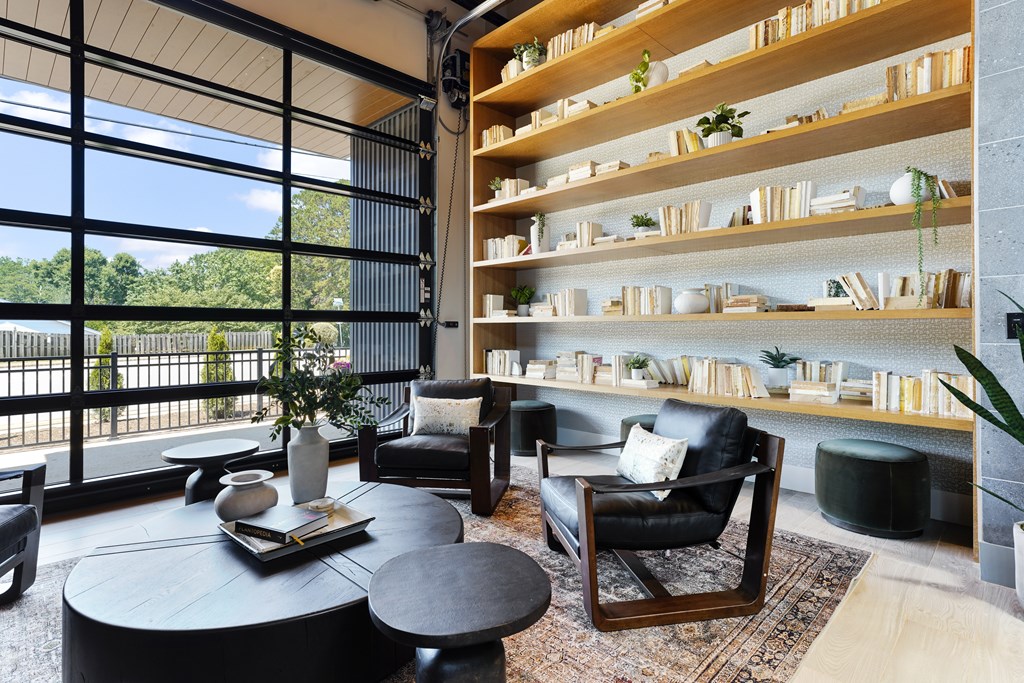 A living room with a black leather chair and a round table.