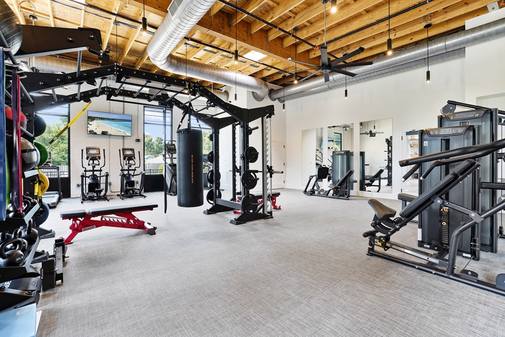 A gym with a variety of equipment including a punching bag, weight bench, and leg press machine.