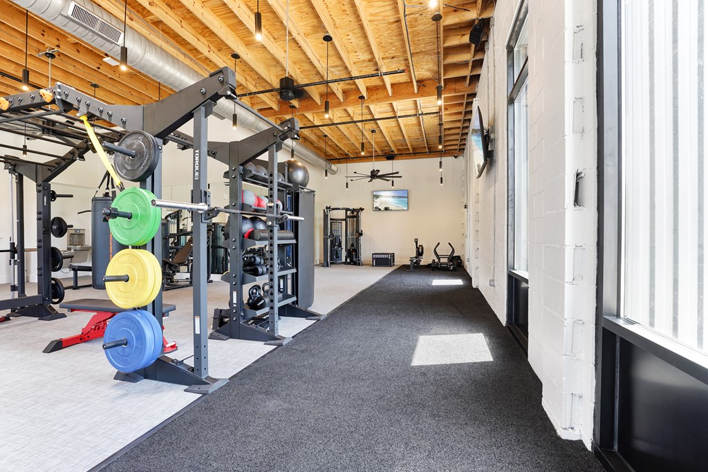 A gym with a variety of equipment including a weight rack and a bench.