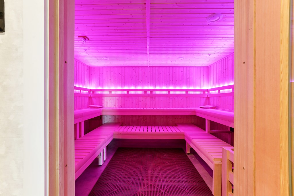 A room with pink lighting and benches.