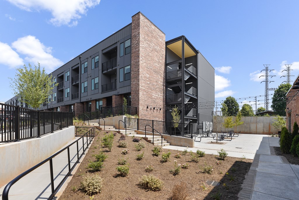 A modern building with a black fence and a small garden in front.