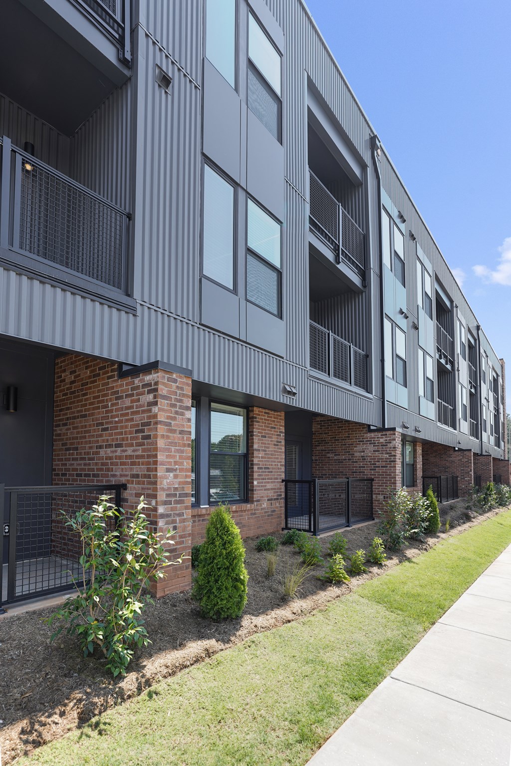 A modern building with grey exterior and brick pillars.