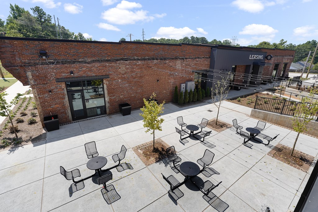 A courtyard with tables and chairs in front of a brick building.