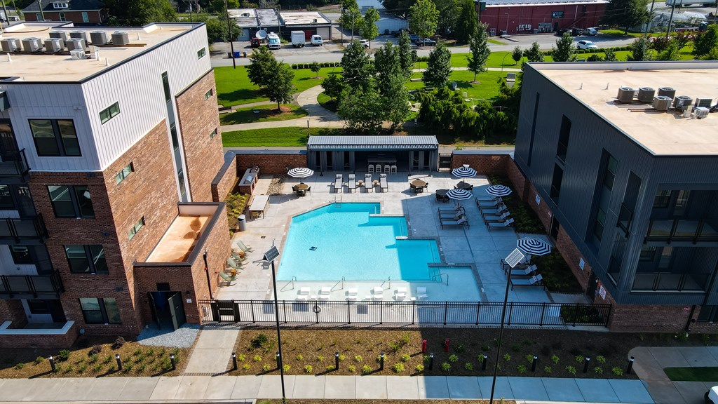 A swimming pool is surrounded by a fence and buildings.