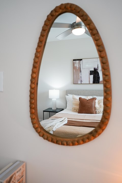 A bedroom with a round mirror on the wall.