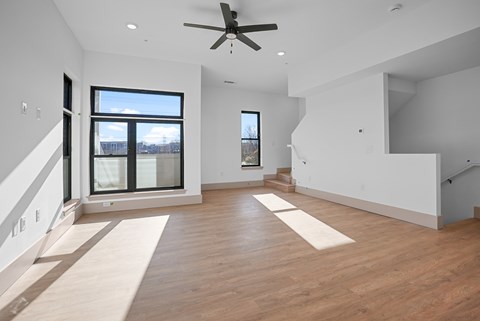 A spacious room with a ceiling fan and large windows.