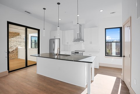 A modern kitchen with white cabinets and a black countertop.