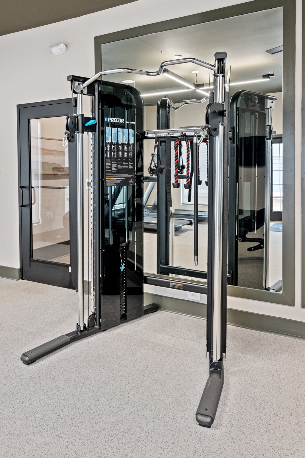 a fitness room with cardio machines and a glass door