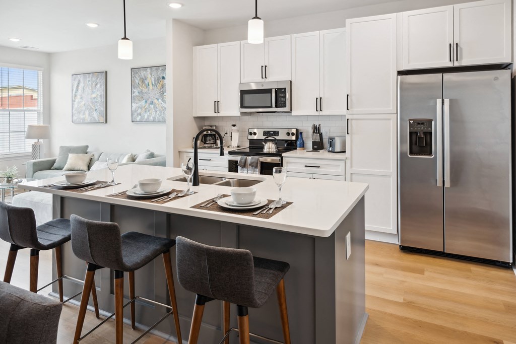 an open kitchen and living room with a large island and stainless steel appliances