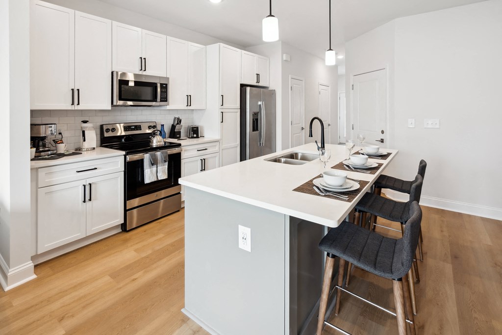 a kitchen with white cabinets and a white island with three stools