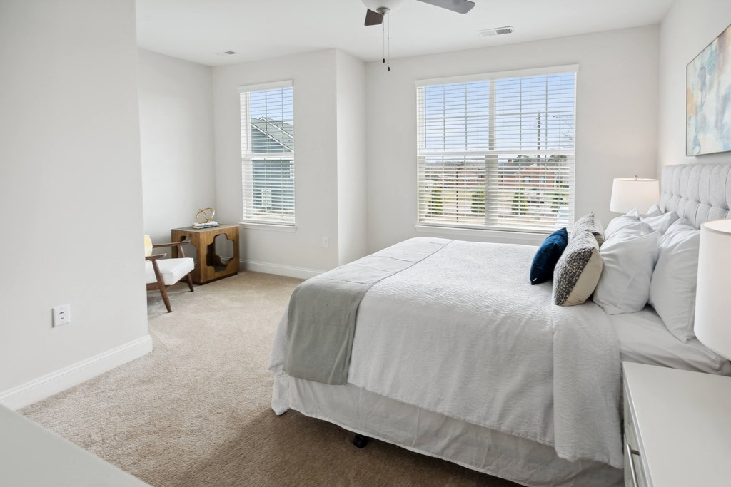 a bedroom with a large bed and two windows
