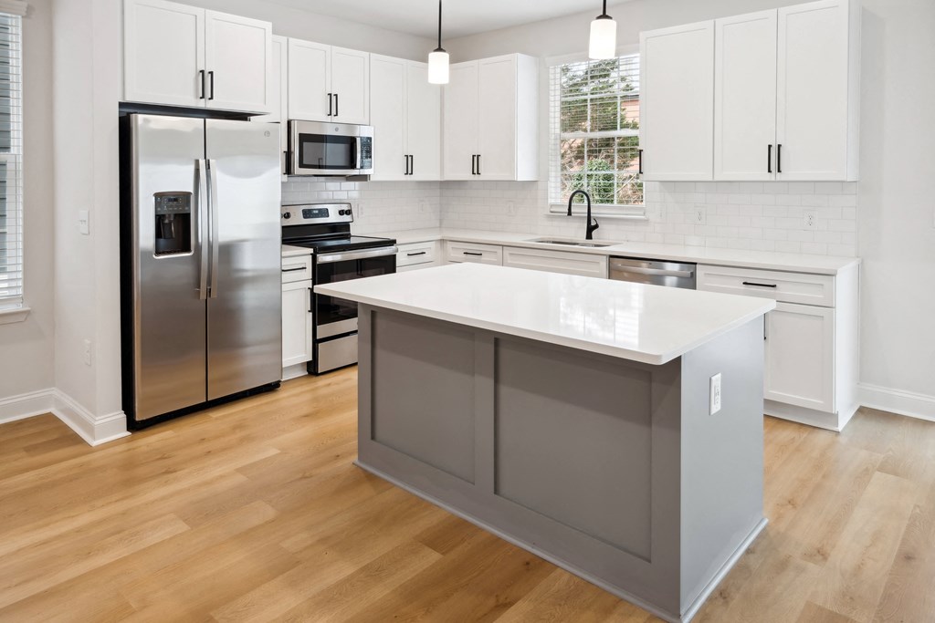 a kitchen with white cabinets and stainless steel appliances and a white counter top