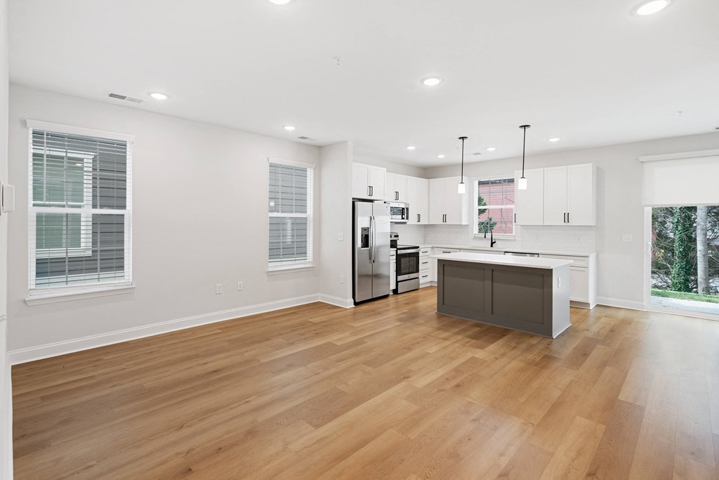 an open kitchen and living room with white walls and wood floors