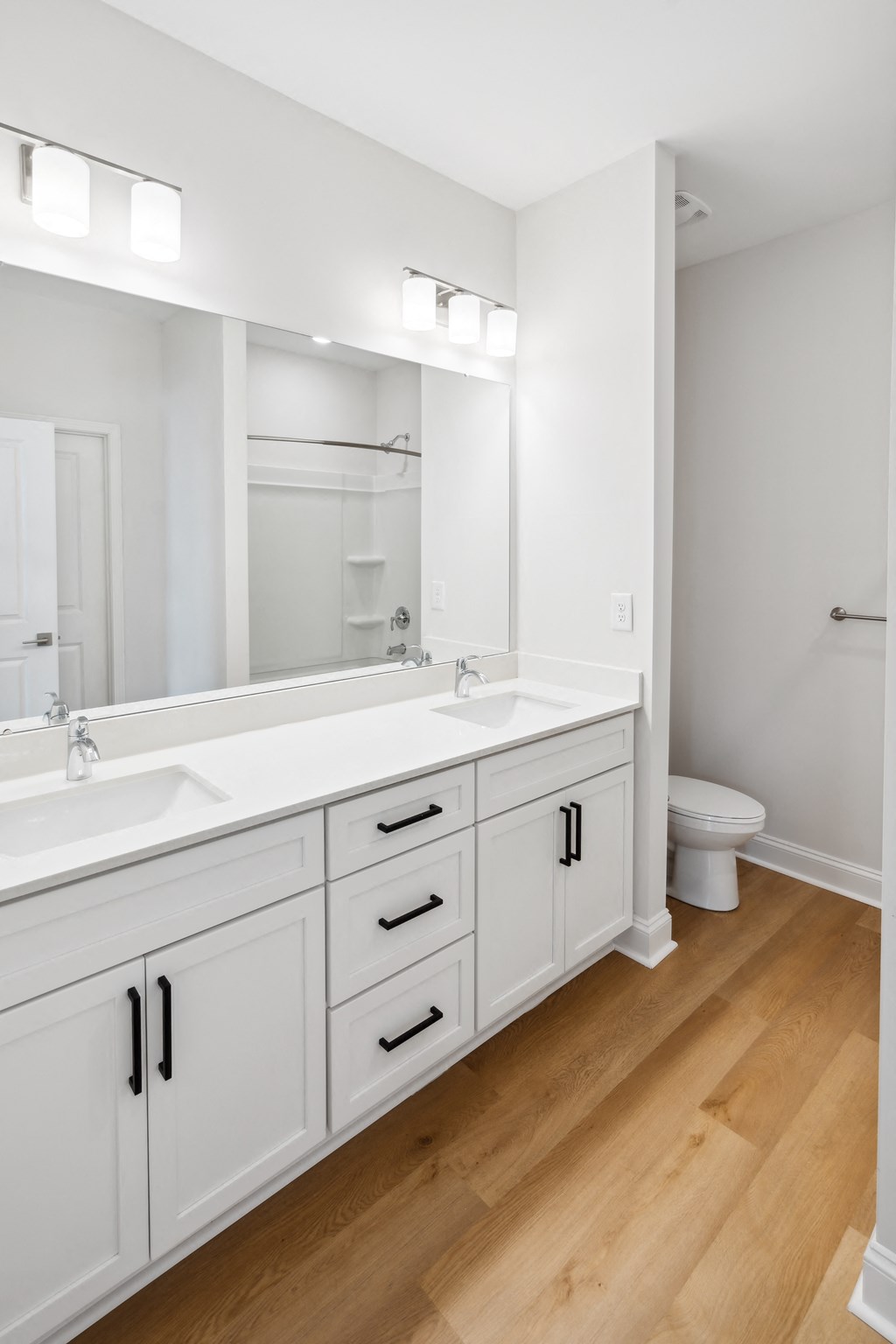 a large white bathroom with two sinks and a mirror