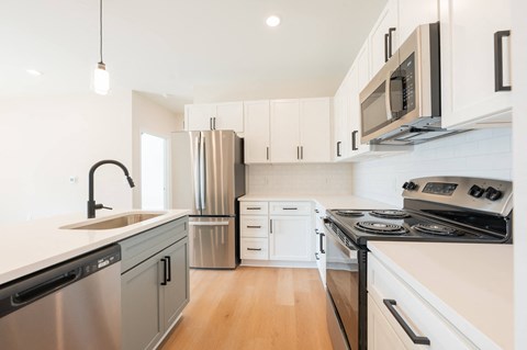 A modern kitchen with white cabinets and stainless steel appliances.
