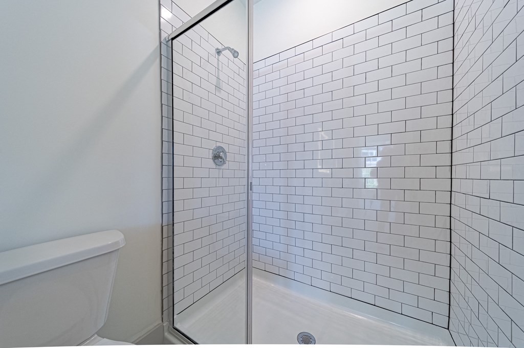a bathroom with white subway tile and a glass shower door