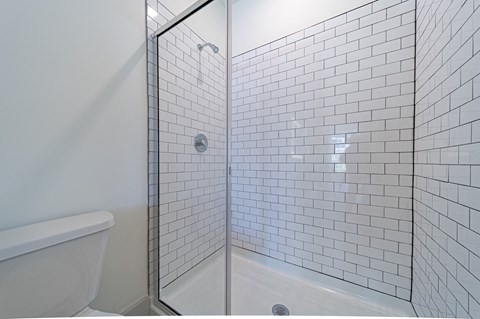 a bathroom with white subway tile and a glass shower door