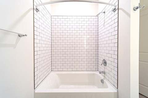 a bathroom with white subway tile and a white bathtub