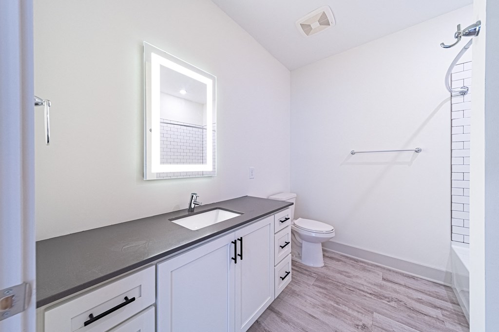 a bathroom with white cabinets and a gray countertop