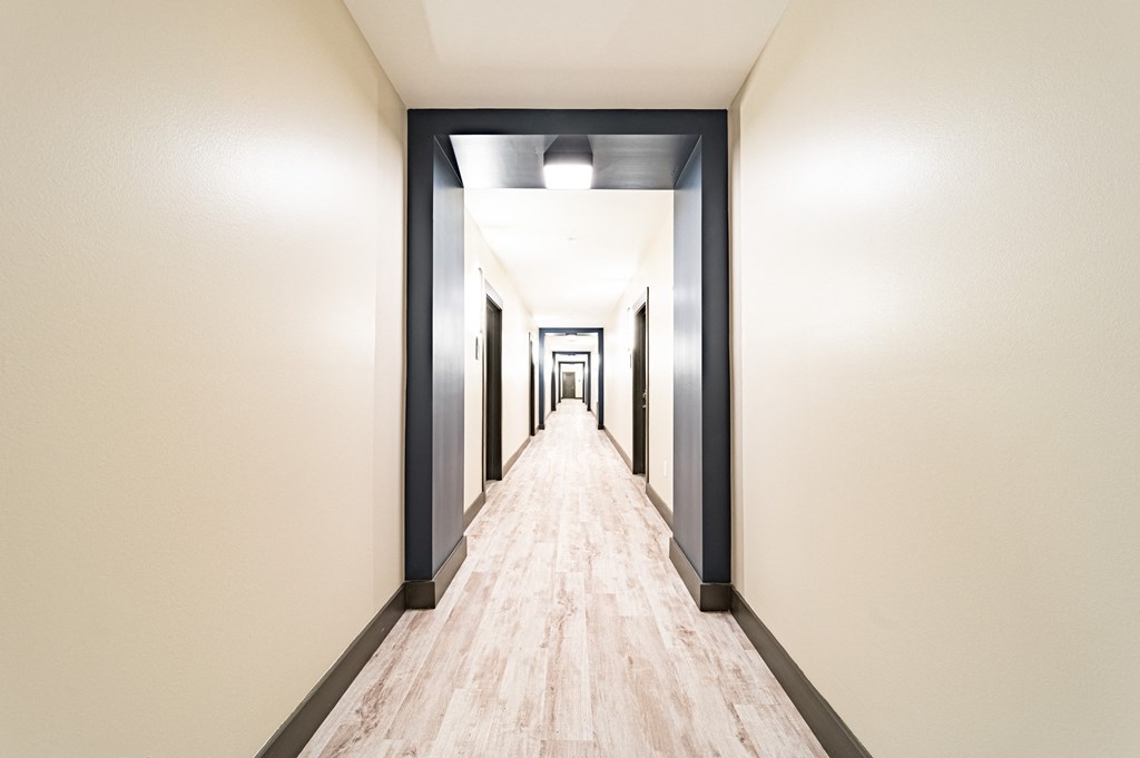 a long corridor with white walls and wood floors