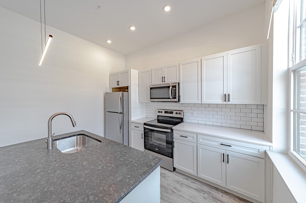 a kitchen with white cabinets and a gray counter top