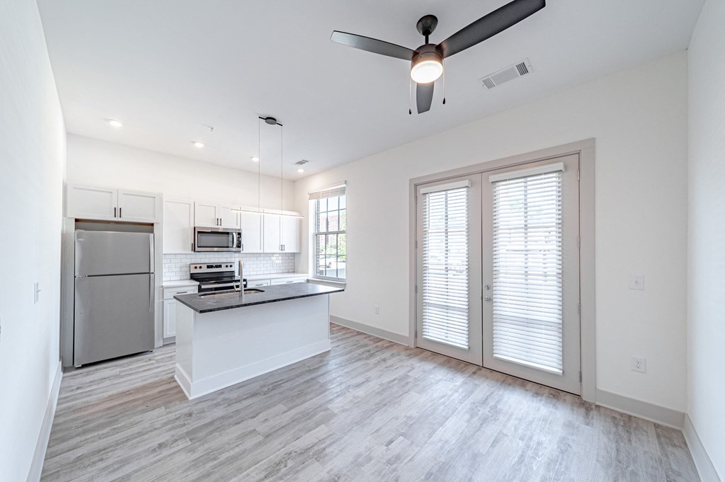 a kitchen and living room with white walls and a ceiling fan