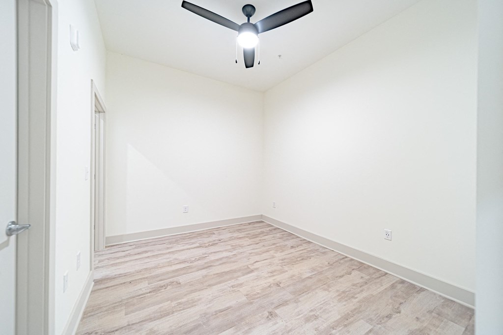 a bedroom with white walls and a ceiling fan