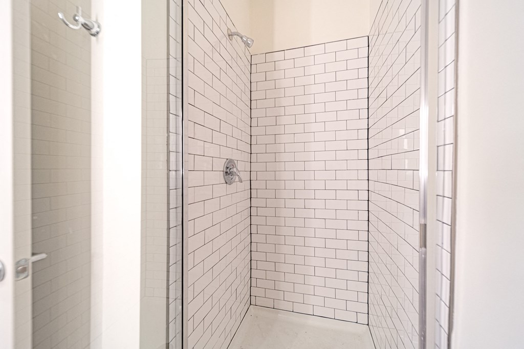 a bathroom with white subway tiles and a glass shower door