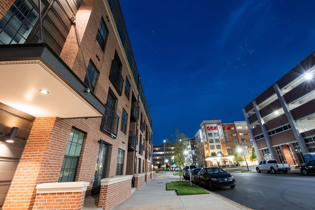 a city street at night with a brick building and cars parked