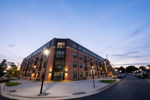 a large brick building on the corner of a street at dusk