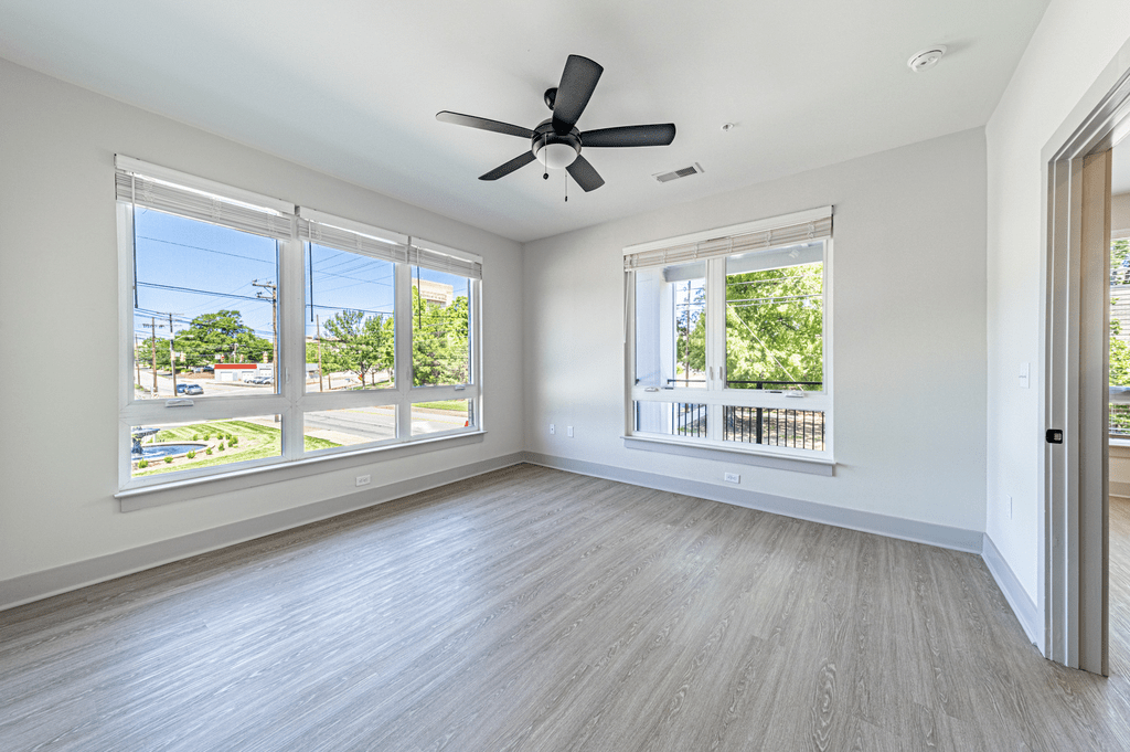 an empty bedroom with a ceiling fan and three windows at The Fitzgerald, Spartanburg, 29302