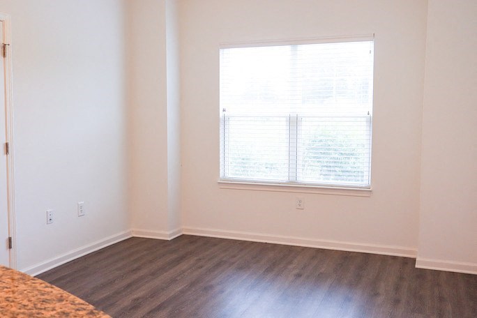 an empty living room with a large window and wooden floors
