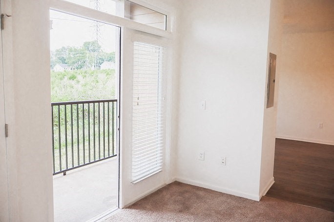 A room with a sliding door leading to a balcony.