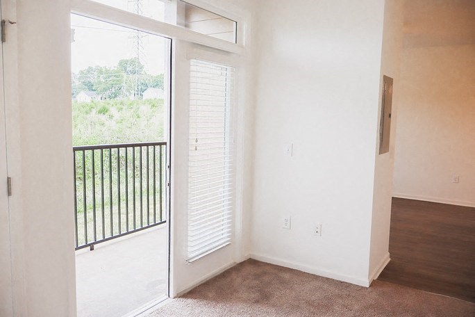 an empty living room with a door to a balcony