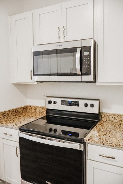 a white kitchen with a stove and a microwave