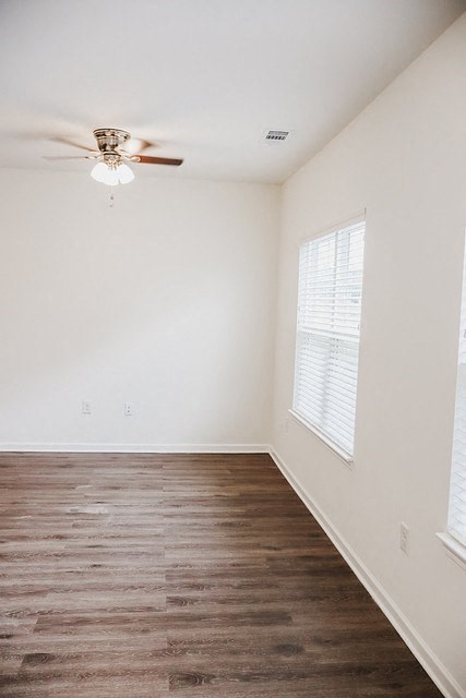 A room with a ceiling fan and wooden flooring.