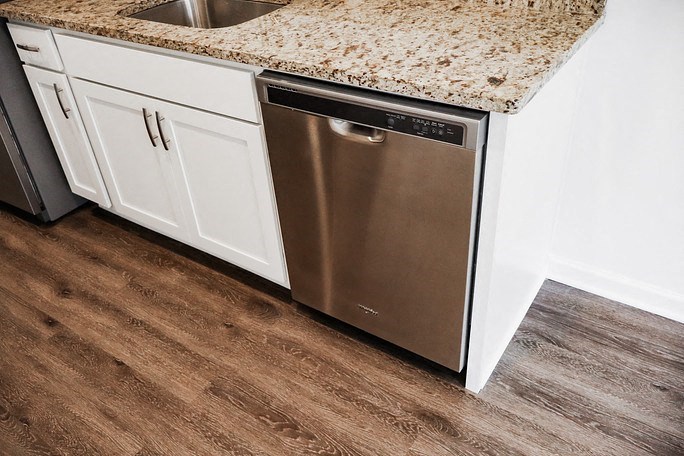 a stainless steel dishwasher in a kitchen with white cabinets