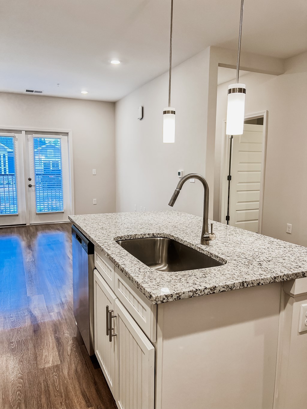 A kitchen with a granite countertop and a stainless steel sink.