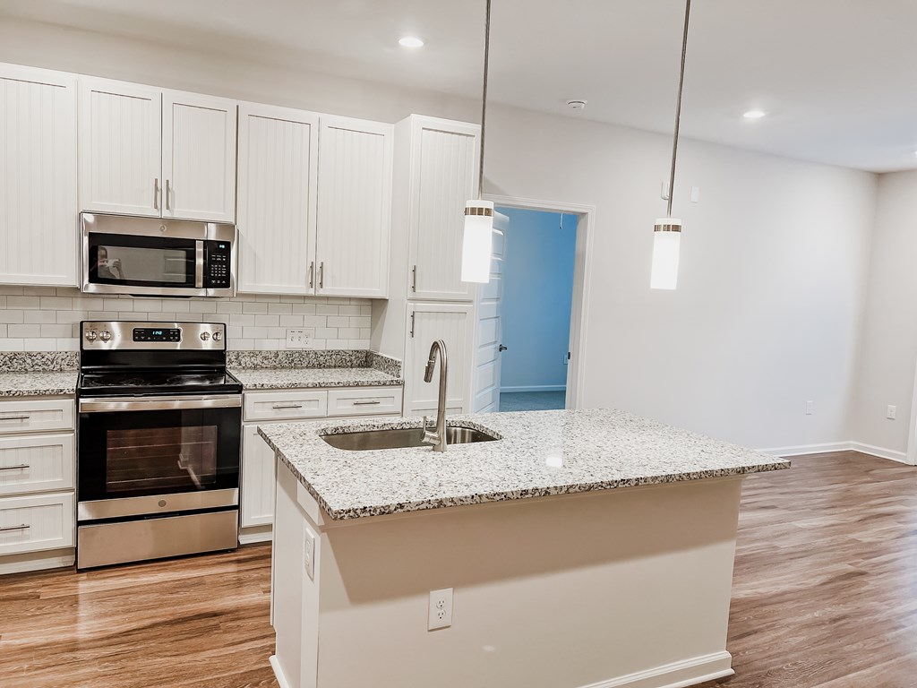 A kitchen with white cabinets and a granite countertop.