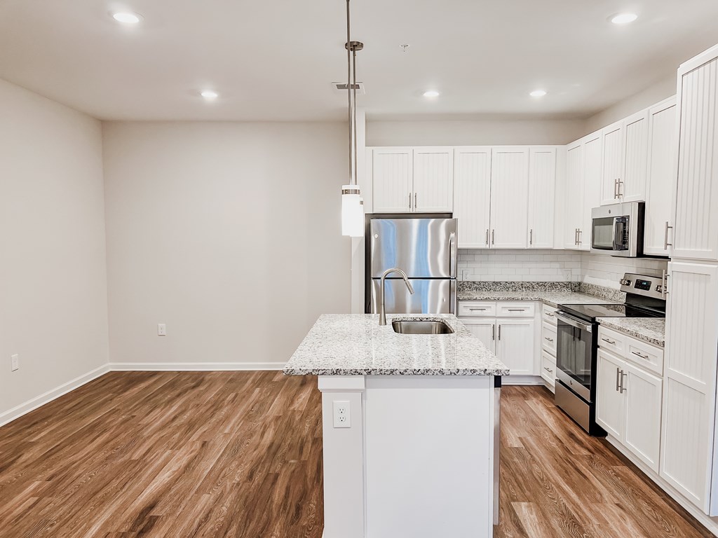 A kitchen with white cabinets and a granite countertop.