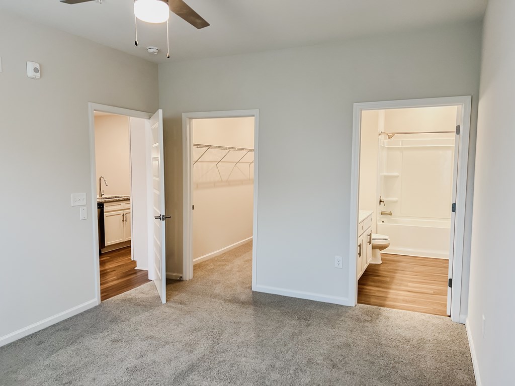 A room with a ceiling fan and three open doors.