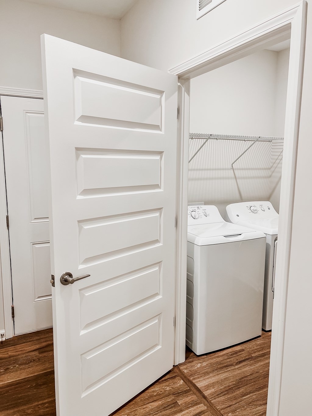 A white door is open to a laundry room with a washer and dryer.