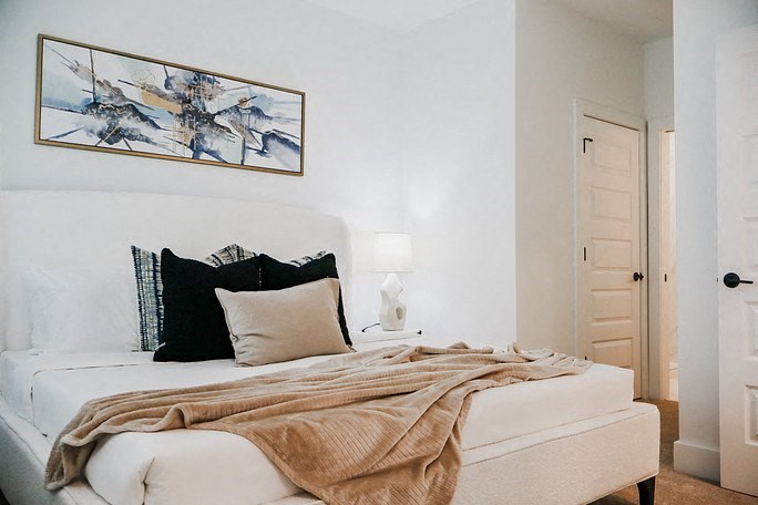 a bedroom with a white bed and a painting on the wall