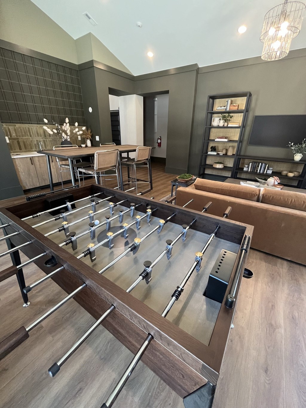 a foosball table sits in the middle of a room with couches and a bar at Landon Green Artisan Cottages Apartments, Hickory, NC
